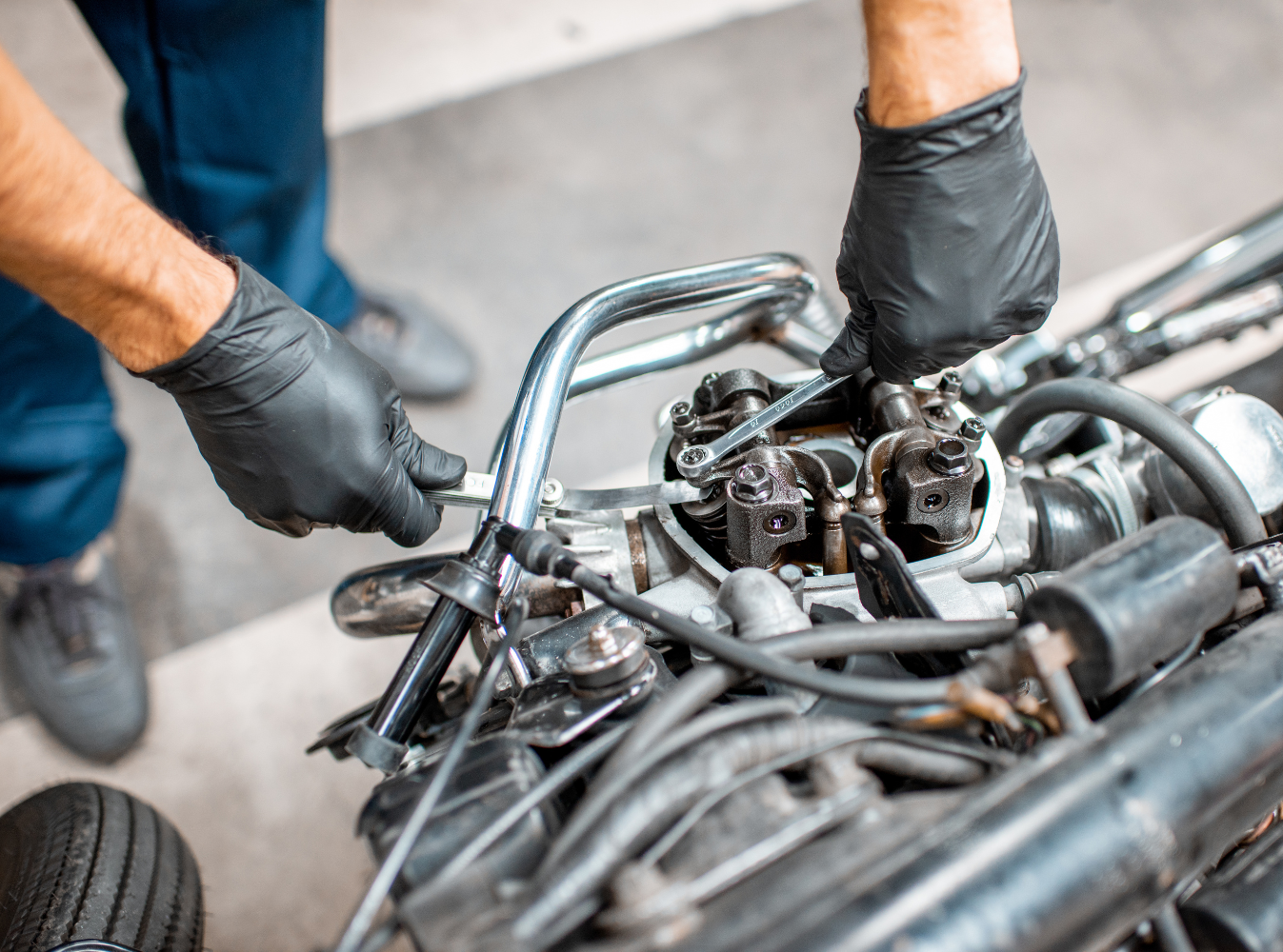 a person with black gloves working on a motorcycle engine