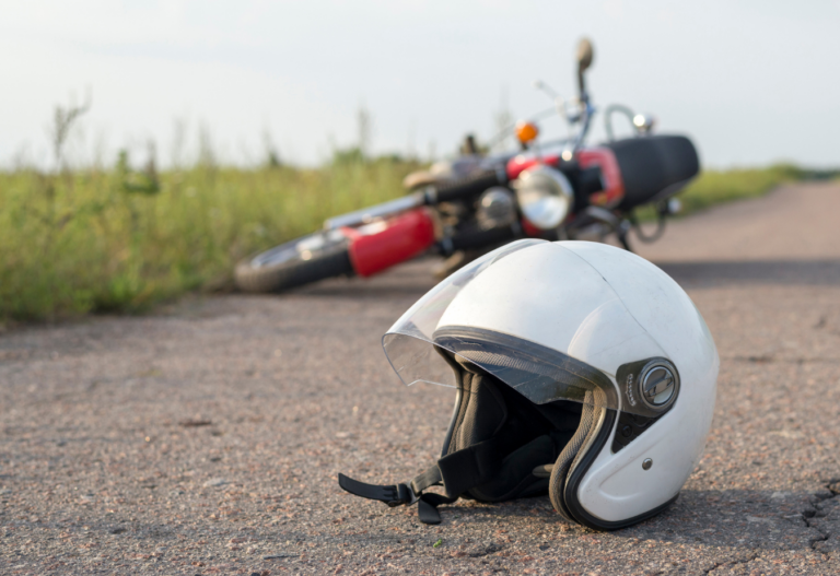 white helmet in the foreground and tipped over motorcycle in the background
