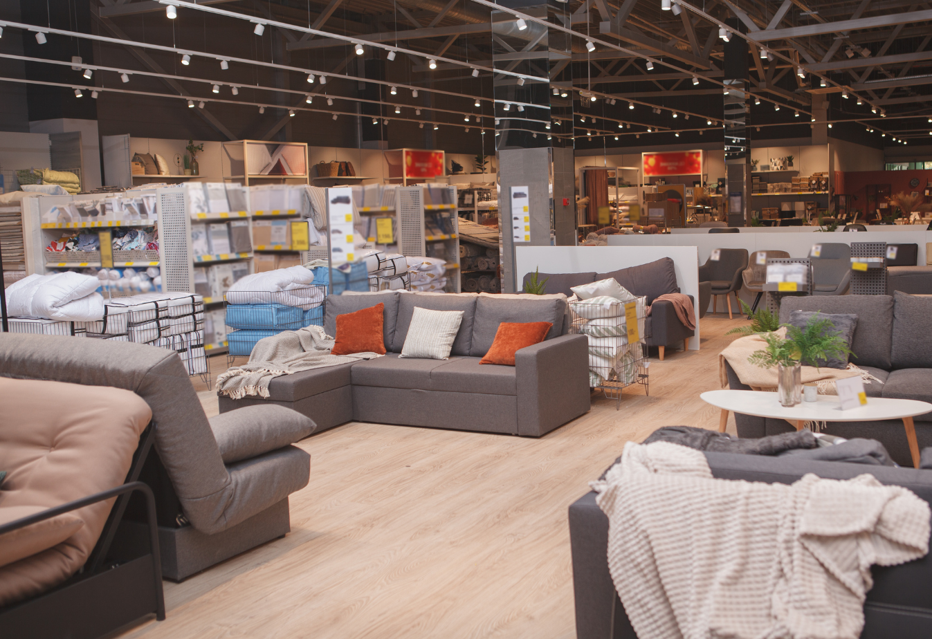wide shot of a furniture and home goods store with grey couch in front of a show room