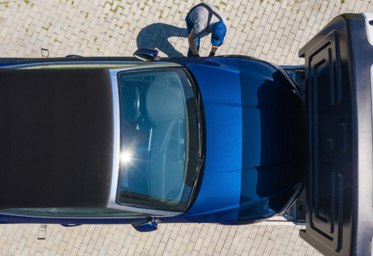 overhead view of a blue sedan on a tow truck
