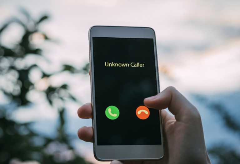 a person's hand holding a smart phone and screen says unknown caller