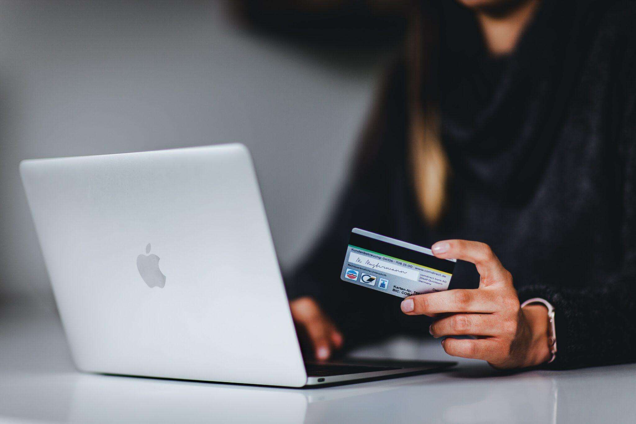 a woman holding a credit card in front of a laptop